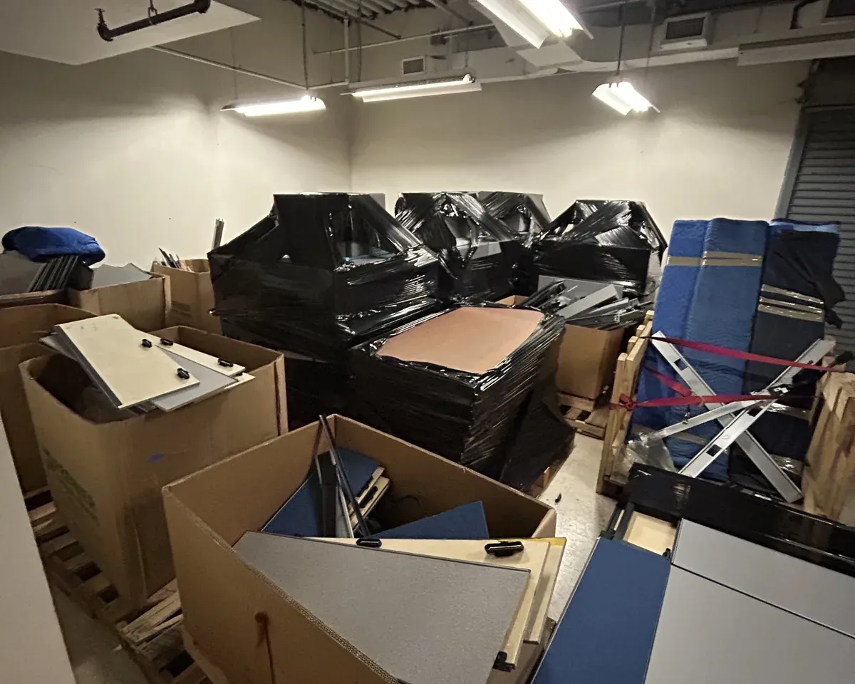 Crowded storage room packed with furniture, boxes, and moving pads before a commercial decommissioning in New York City